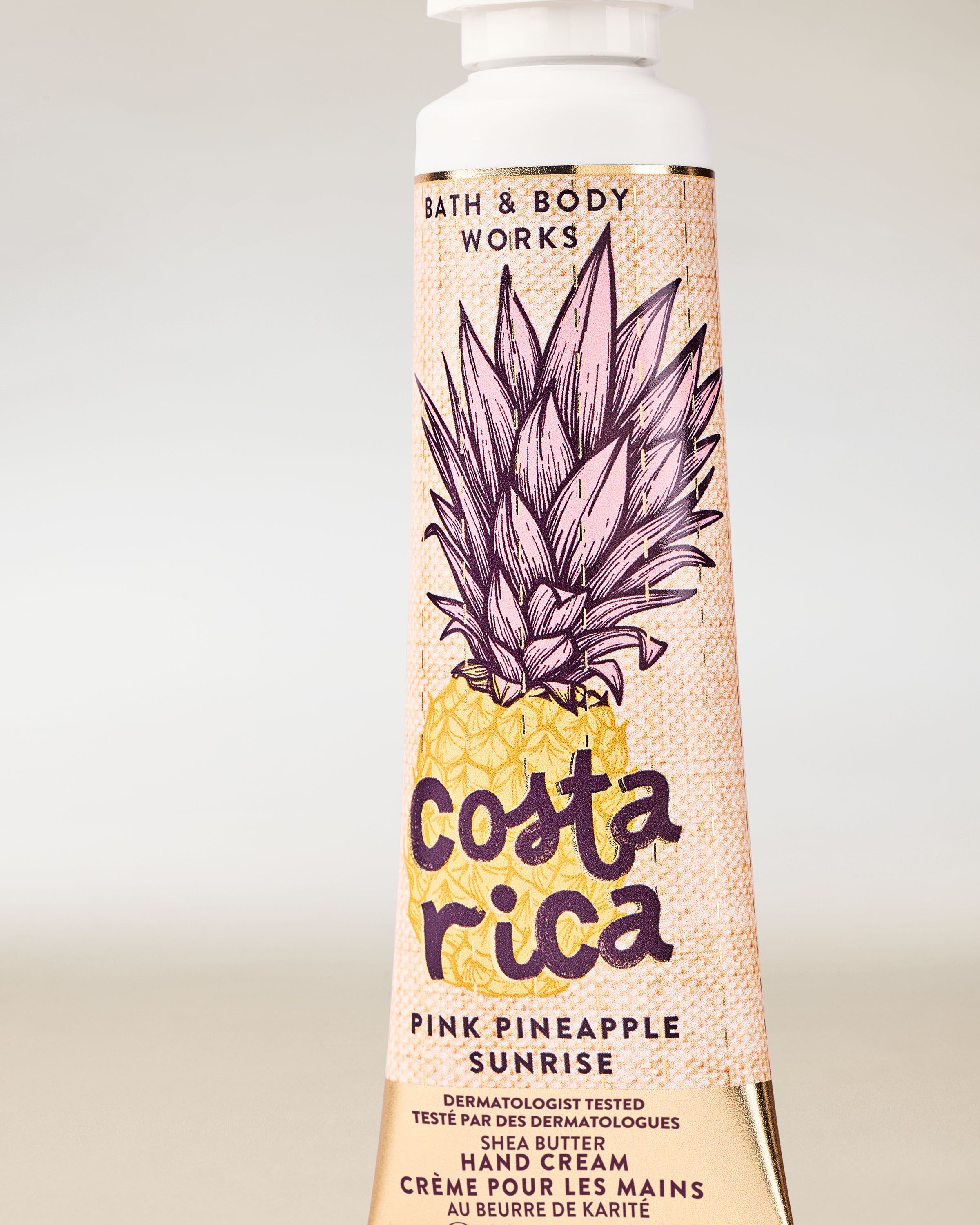 Krem do rąk Costa Rica Pink Pineapple Sunrise w żółtej tubie z ilustracją ananasa i tropikalnym motywem.
