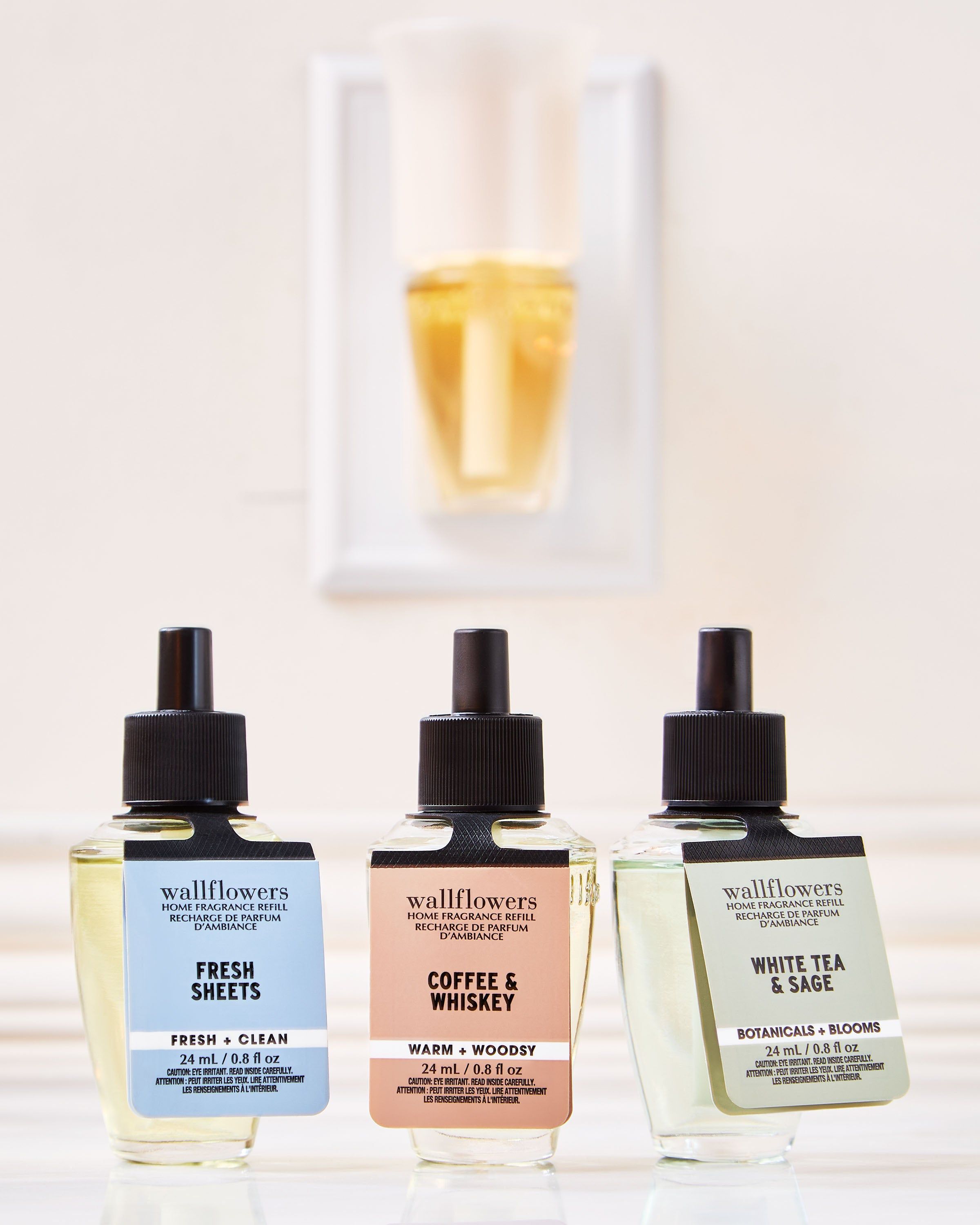 Zestaw refillów Wallflowers: Fresh Sheets, Coffee & Whiskey, White Tea & Sage w szklanych butelkach.