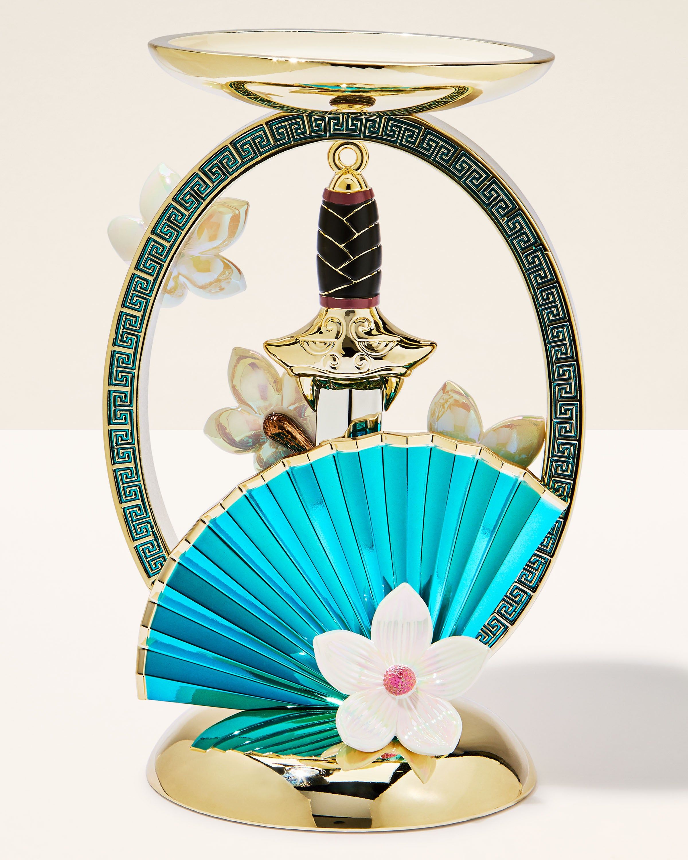 Podstawka Mulan na świecę 3‑knotową ze złotym mieczem, wachlarzem i kwiatami magnolii w ozdobnej ramie.