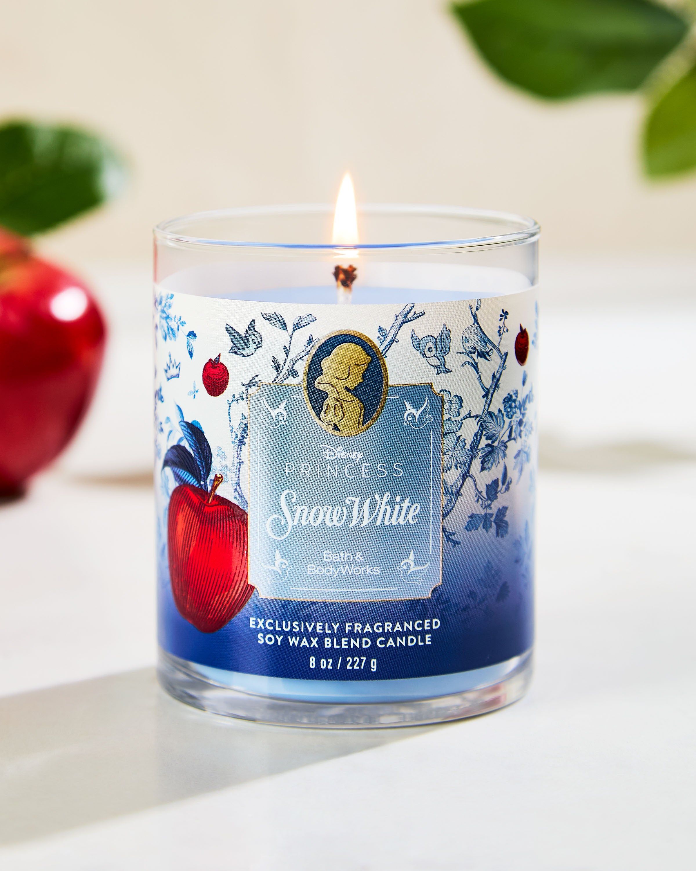 Świeca Snow White z kolekcji Disney Princess — niebieski design z jabłkiem i leśnymi detalami.