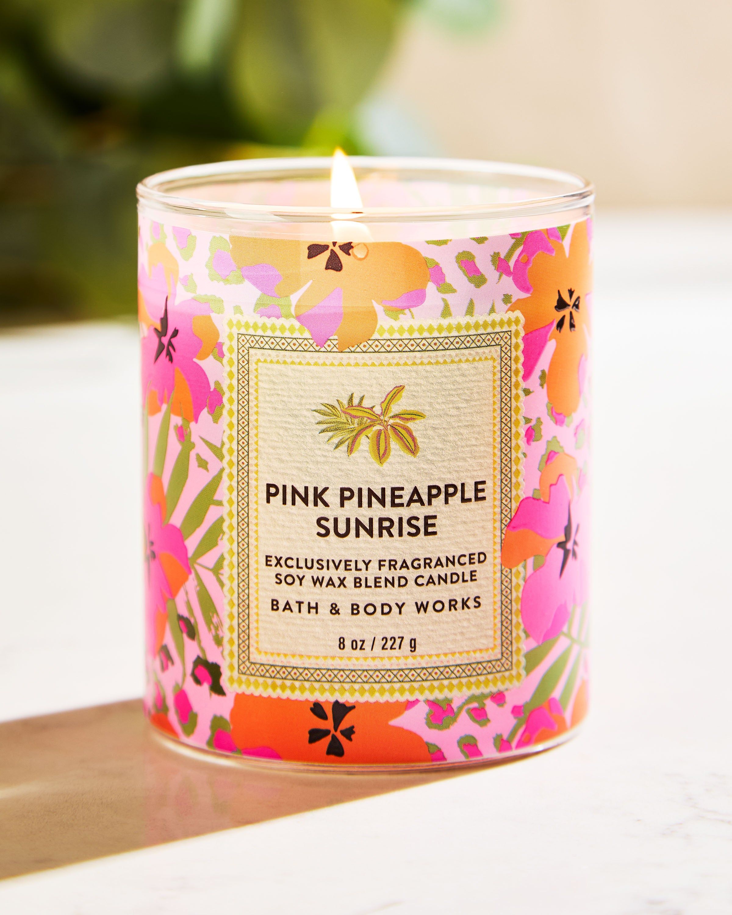 Świeca Pink Pineapple Sunrise z kolorową, tropikalną etykietą w hibiskusy i ananasa – letni, energetyczny design.