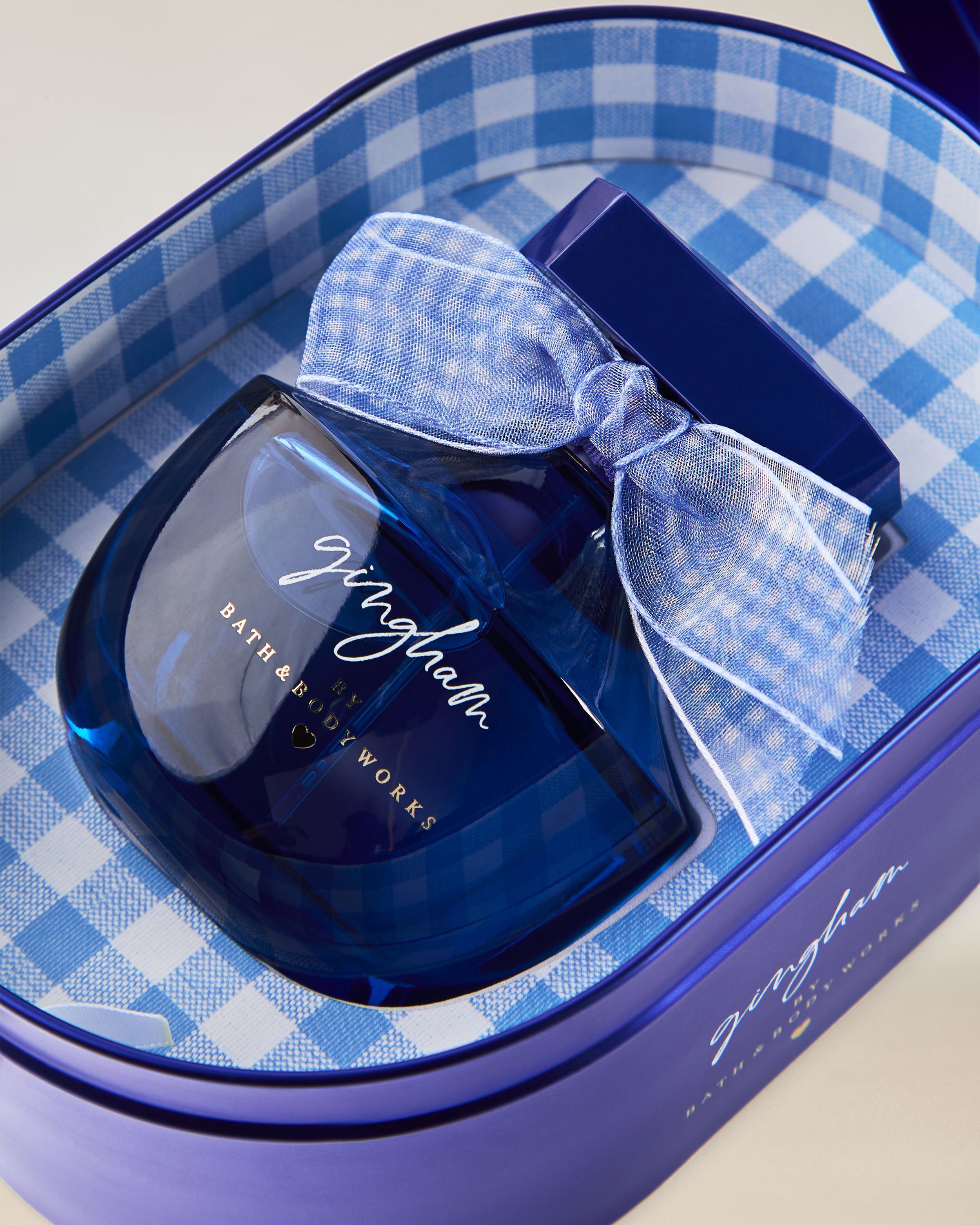 Perfumy Bath & Body Works Gingham w niebieskim szklanym flakonie z dekoracyjną kokardą.