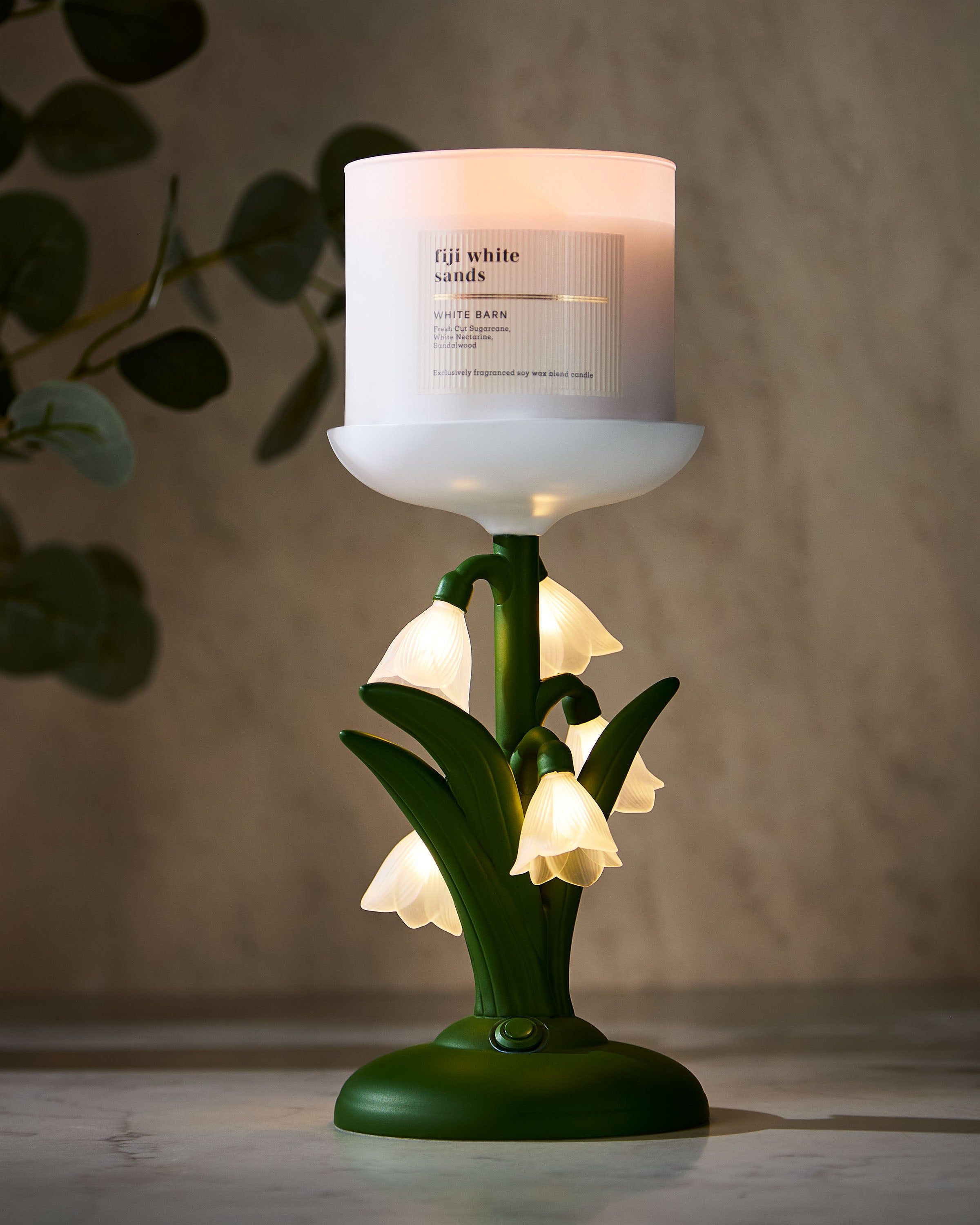 Zielony świecznik Bath & Body Works inspirowany przebiśniegami, z białymi, matowymi kwiatami w 3D.