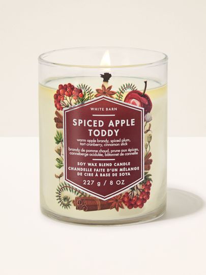 Świeca zapachowa Spiced Apple Toddy White Barn z jednym płonącym knotem i motywem jabłek oraz cynamonu