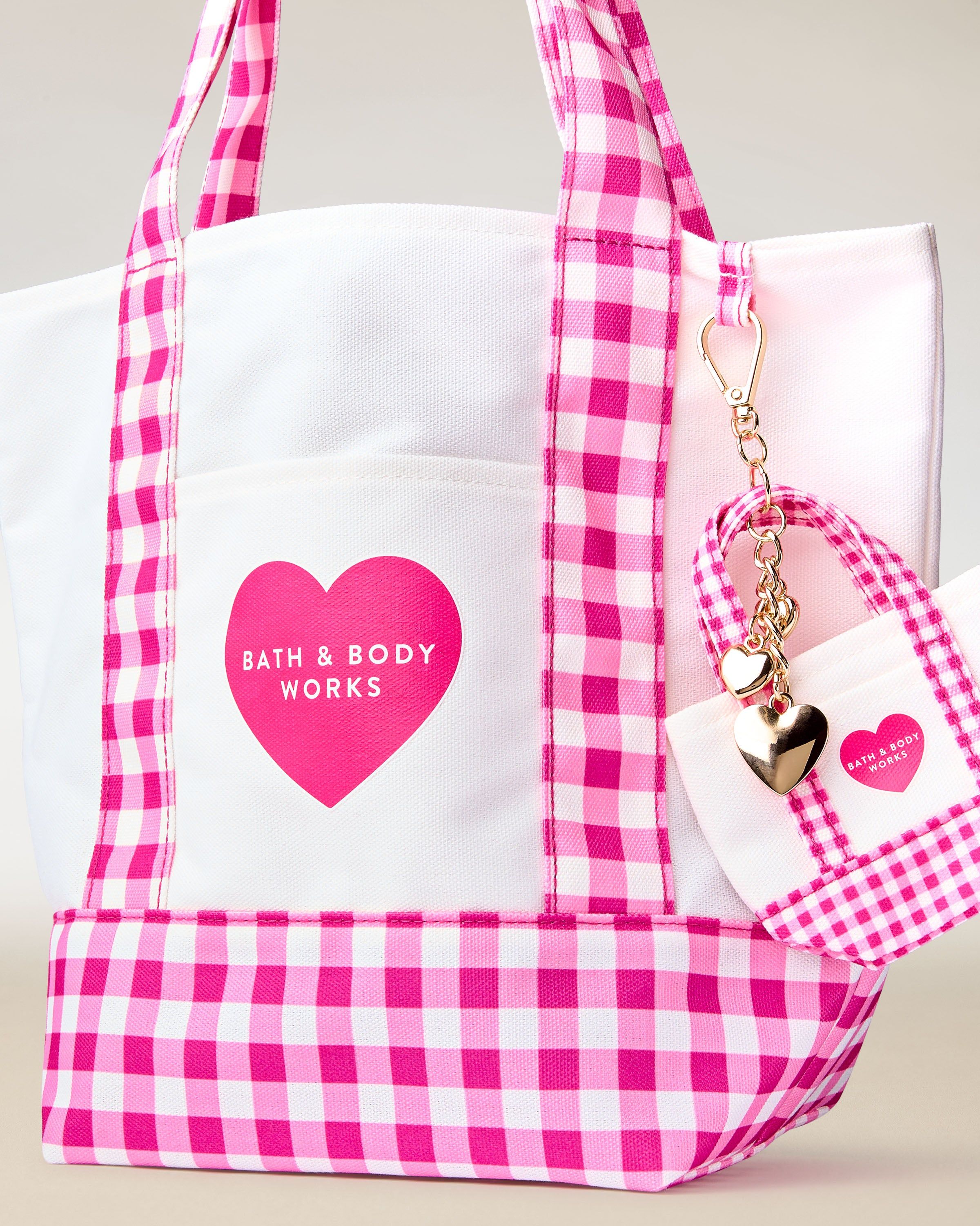 Torba Bath & Body Works w różowo‑białą kratkę gingham z uchwytami i ozdobnym brelokiem.