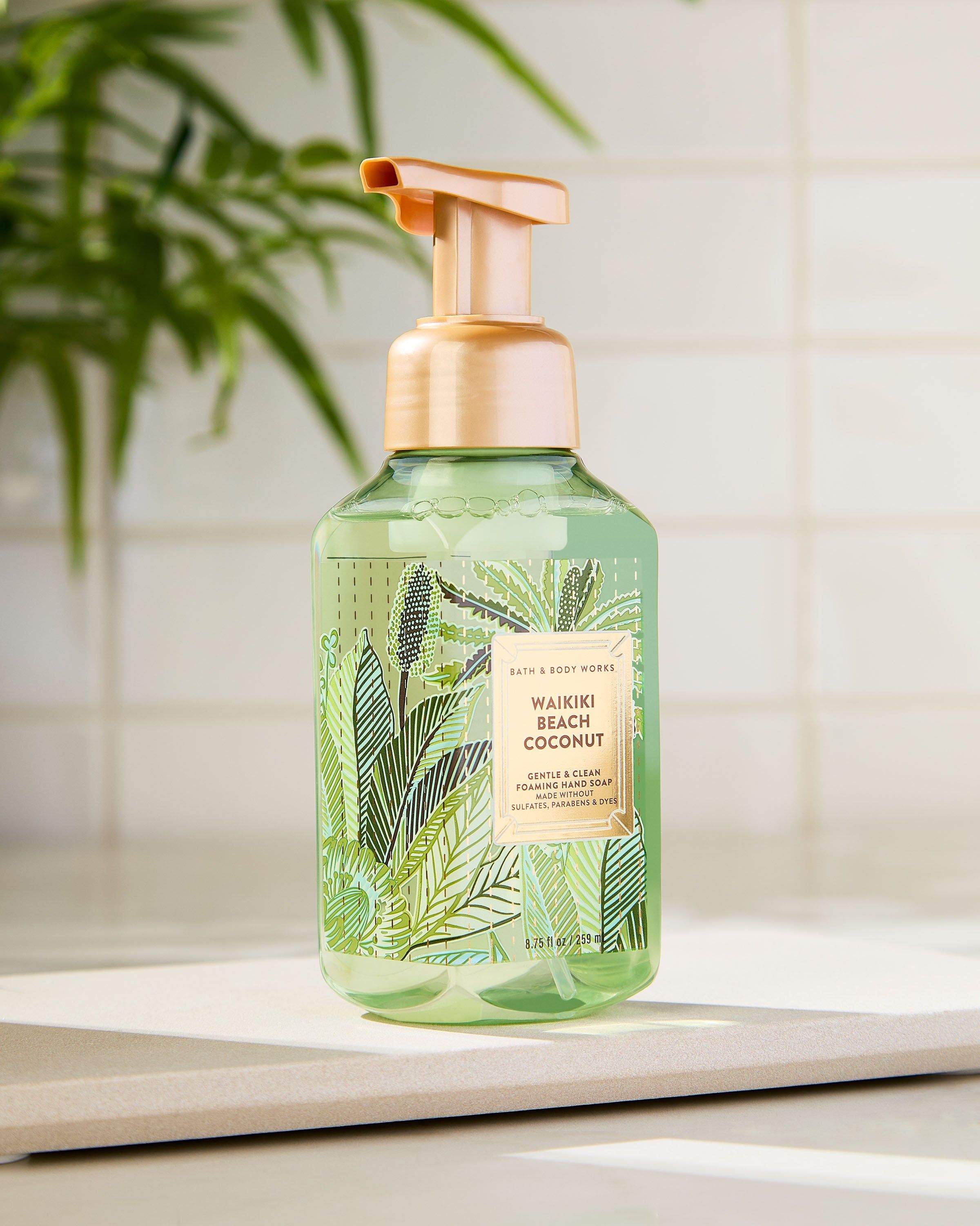 Waikiki Beach Coconut – zielone, transparentne mydło w piance ze złotą pompką i tropikalną etykietą w liście palm.