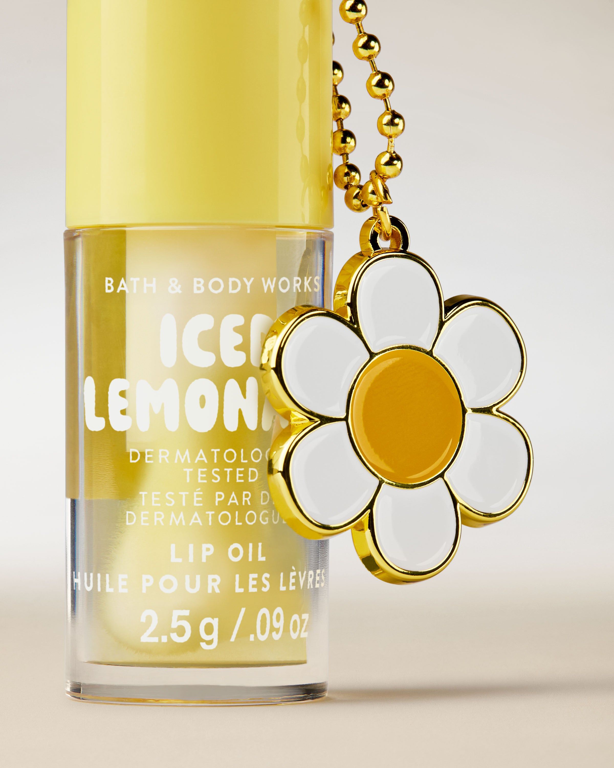 Olejek do ust Bath & Body Works Iced Lemonade 2,5 g w żółtym opakowaniu z brelokiem w kształcie kwiatu.