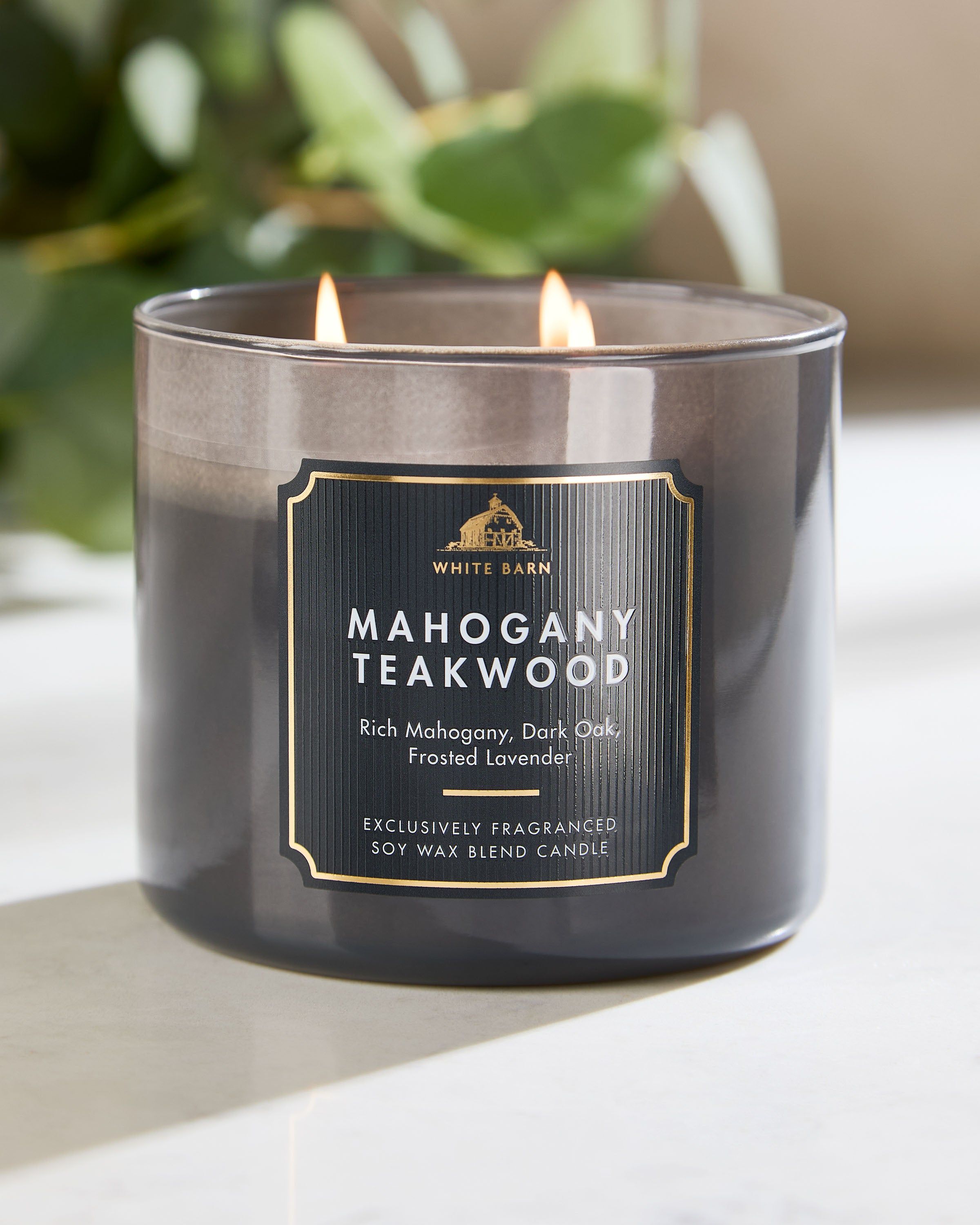 Świeca Mahogany Teakwood w eleganckim szklanym opakowaniu, z charakterystycznym aromatem drewna i subtelnymi akcentami kompozycji White Barn.
