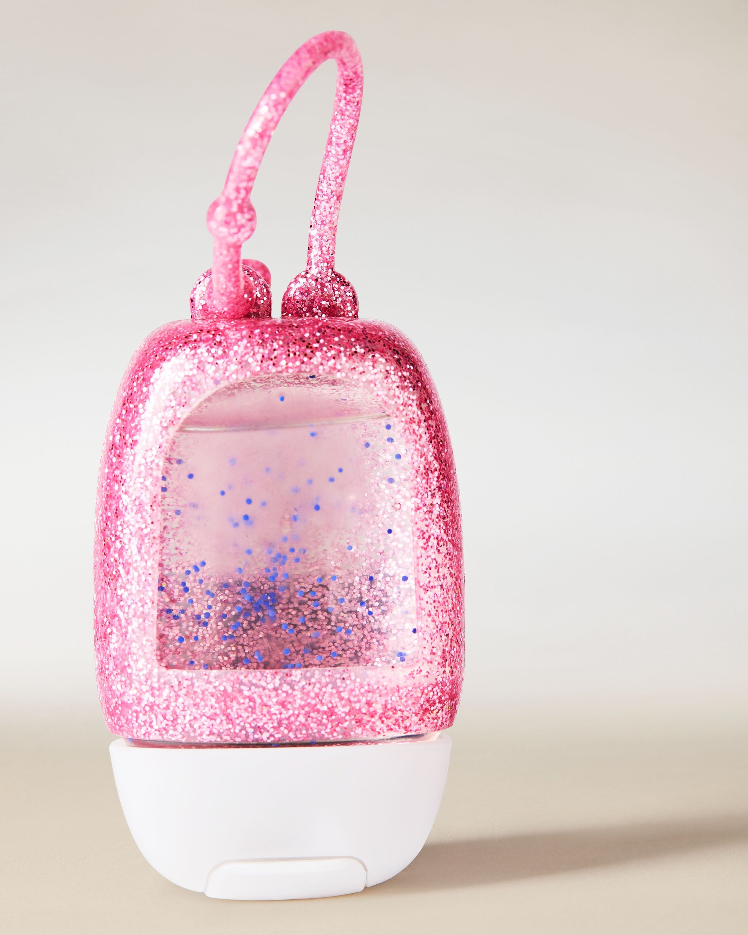 Brokatowy uchwyt PocketBac w intensywnym odcieniu różu, wykonany z elastycznego materiału, zaprojektowany do wygodnego przypięcia mini żelu antybakteryjnego.