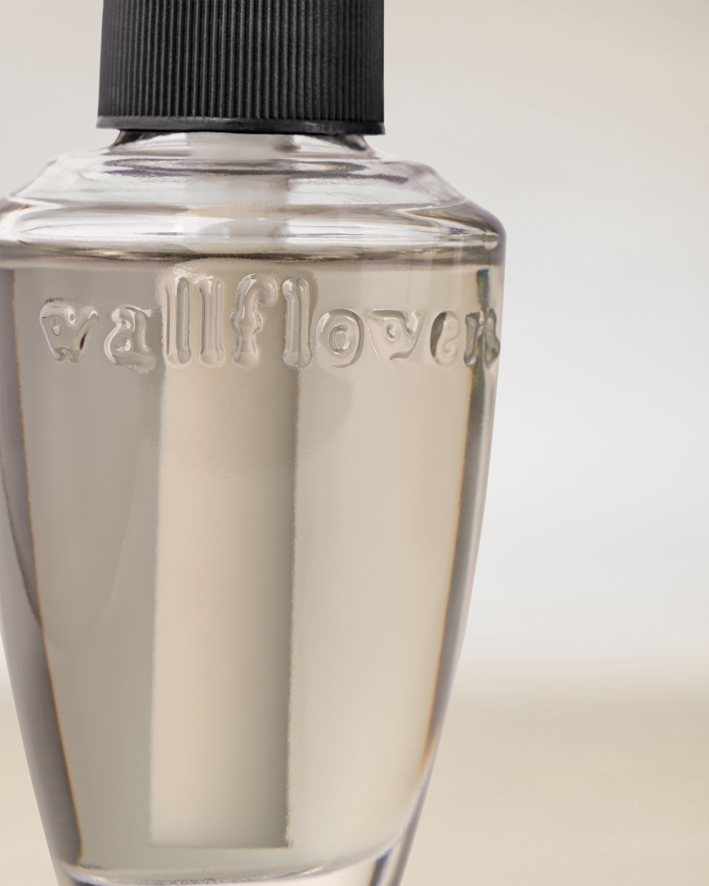 Zbliżenie przezroczystego wkładu Wallflowers z tłoczonym logo — elegancki, minimalistyczny detal.
