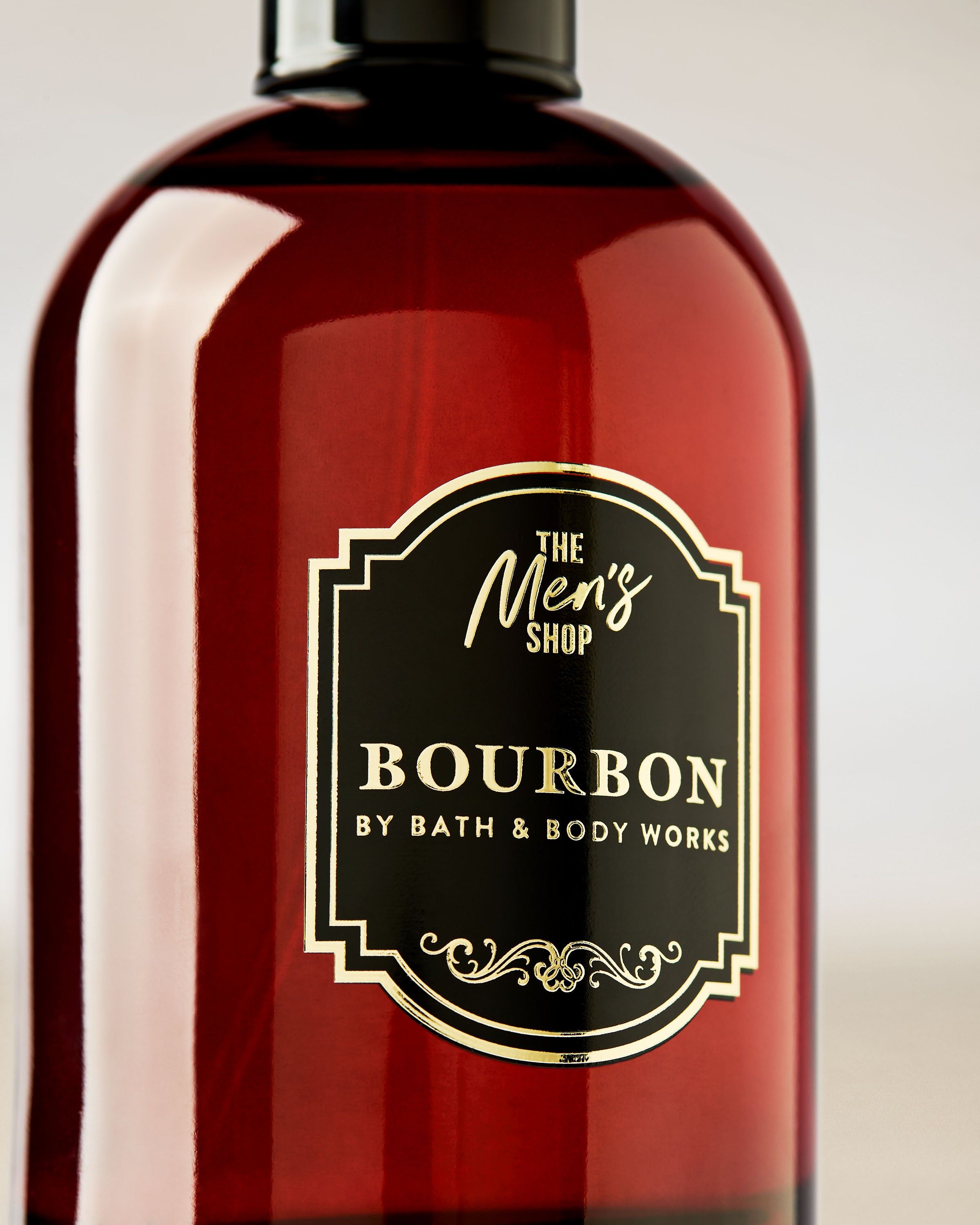 Bath & Body Works Bourbon – ciemnoczerwony flakon z czarną nakrętką i dekoracyjną etykietą w stylu Men’s Shop.