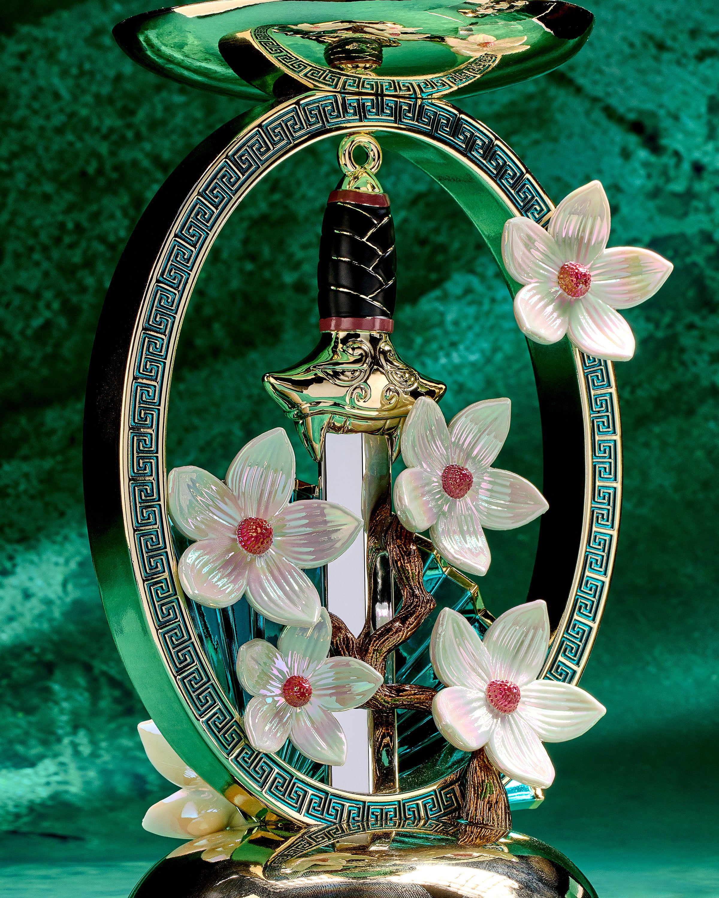 Podstawka Mulan na świecę 3‑knotową ze złotym mieczem, wachlarzem i kwiatami magnolii w ozdobnej ramie.