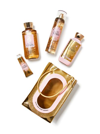 Zestaw prezentowy Bath & Body Works In The Stars: żel, mgiełka, balsam, krem do rąk i ozdobna złota torebka.