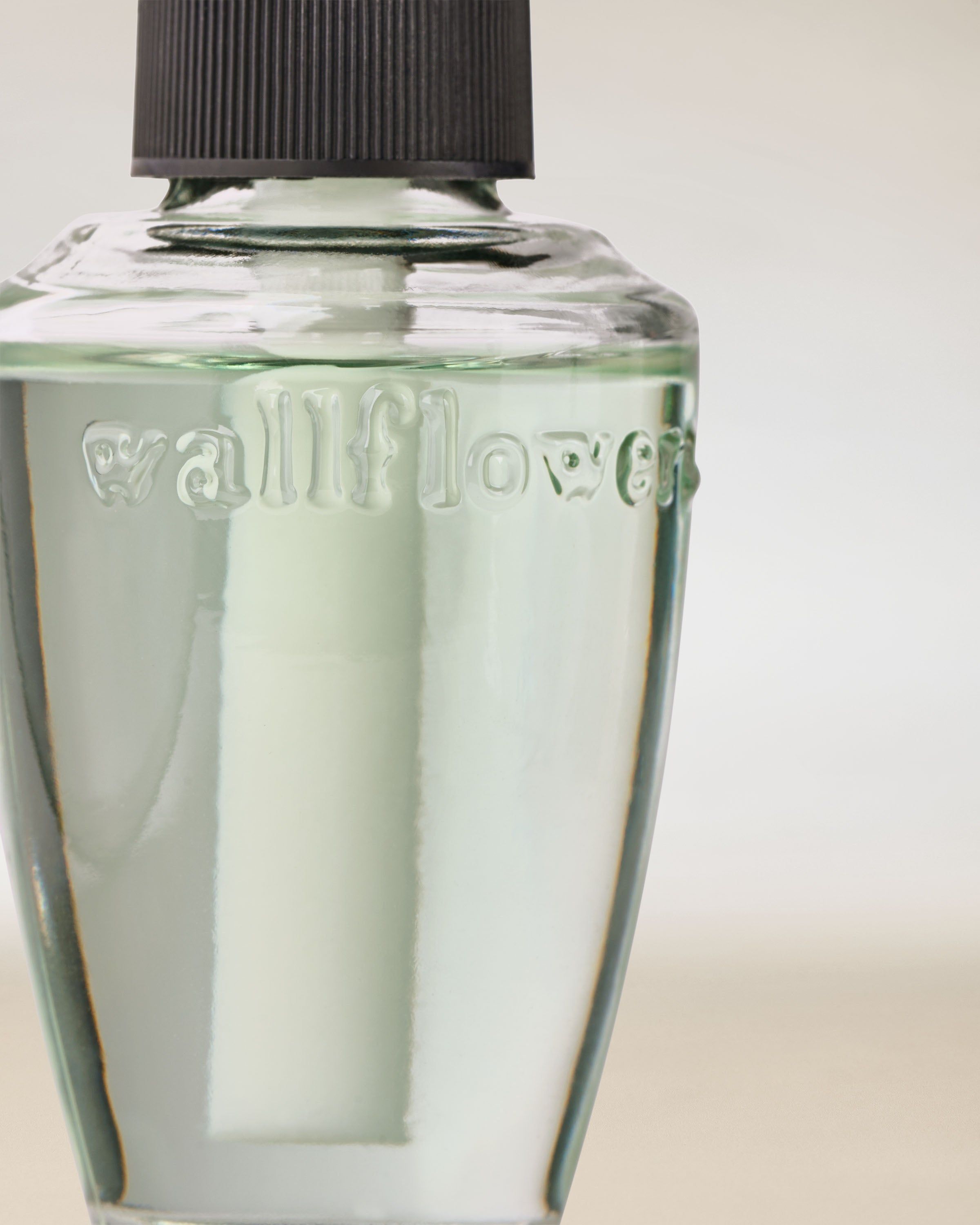 Refill Wallflowers z zielonym płynem – elegancka szklana butelka do odświeżacza wnętrz.