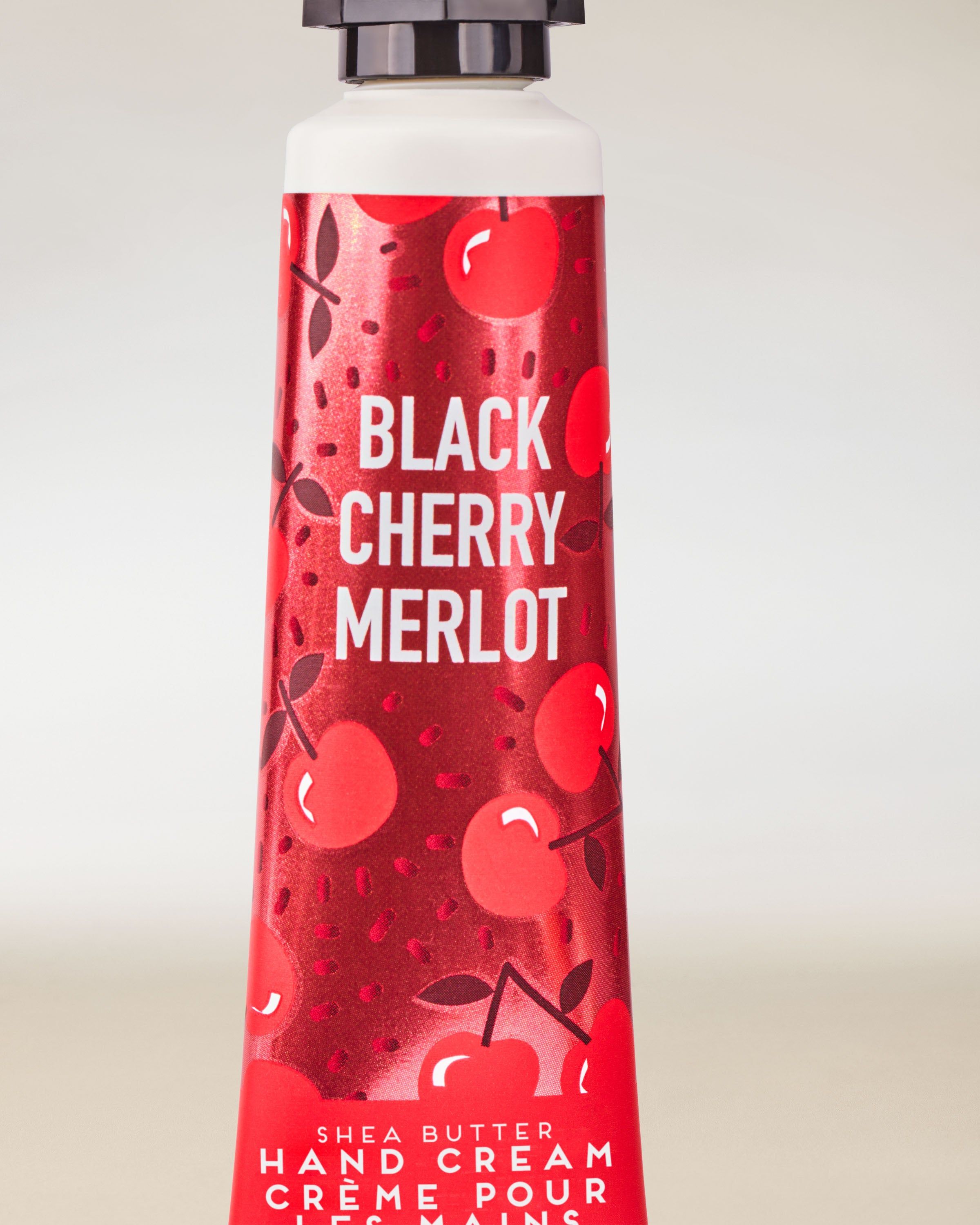 Krem do rąk Black Cherry Merlot od Bath & Body Works w czerwonej tubce z wiśniową, dekoracyjną grafiką.