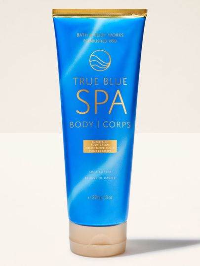 Krem do ciała Bath&Body Works True Blue Spa. Niebieska tubka ze złotym paskiem i beżową nakrętką, z napisami.