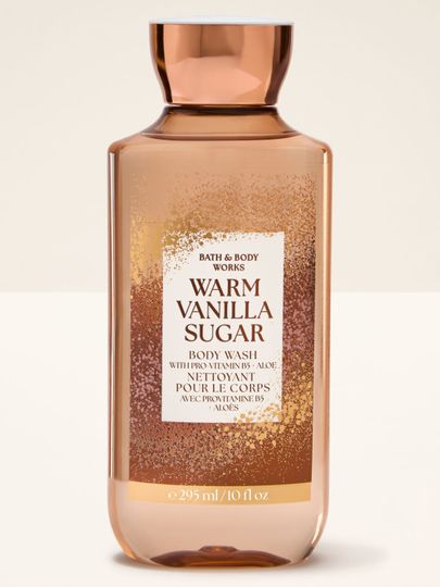 Żel pod prysznic Bath & Body Works "Warm Vanilla Sugar" w pomarańczowej butelce z brokatową etykietą.