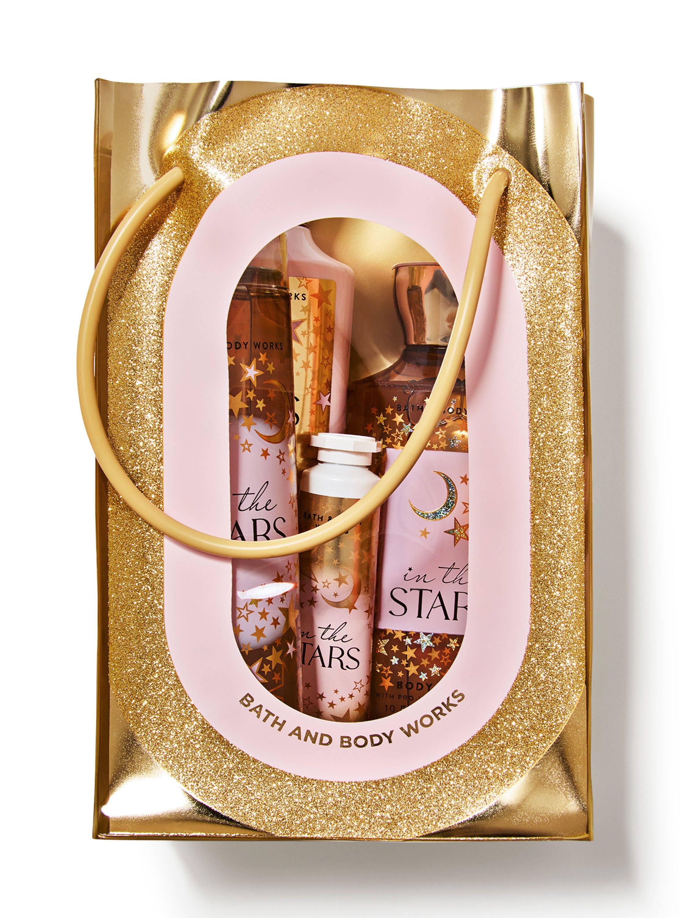 Zestaw Bath & Body Works In The Stars zapakowany w błyszczącą, złotą torebkę prezentową z przezroczystym okienkiem.